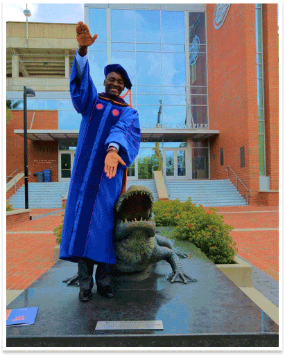 Young man in graduation robe makes gator snap gesture with hands